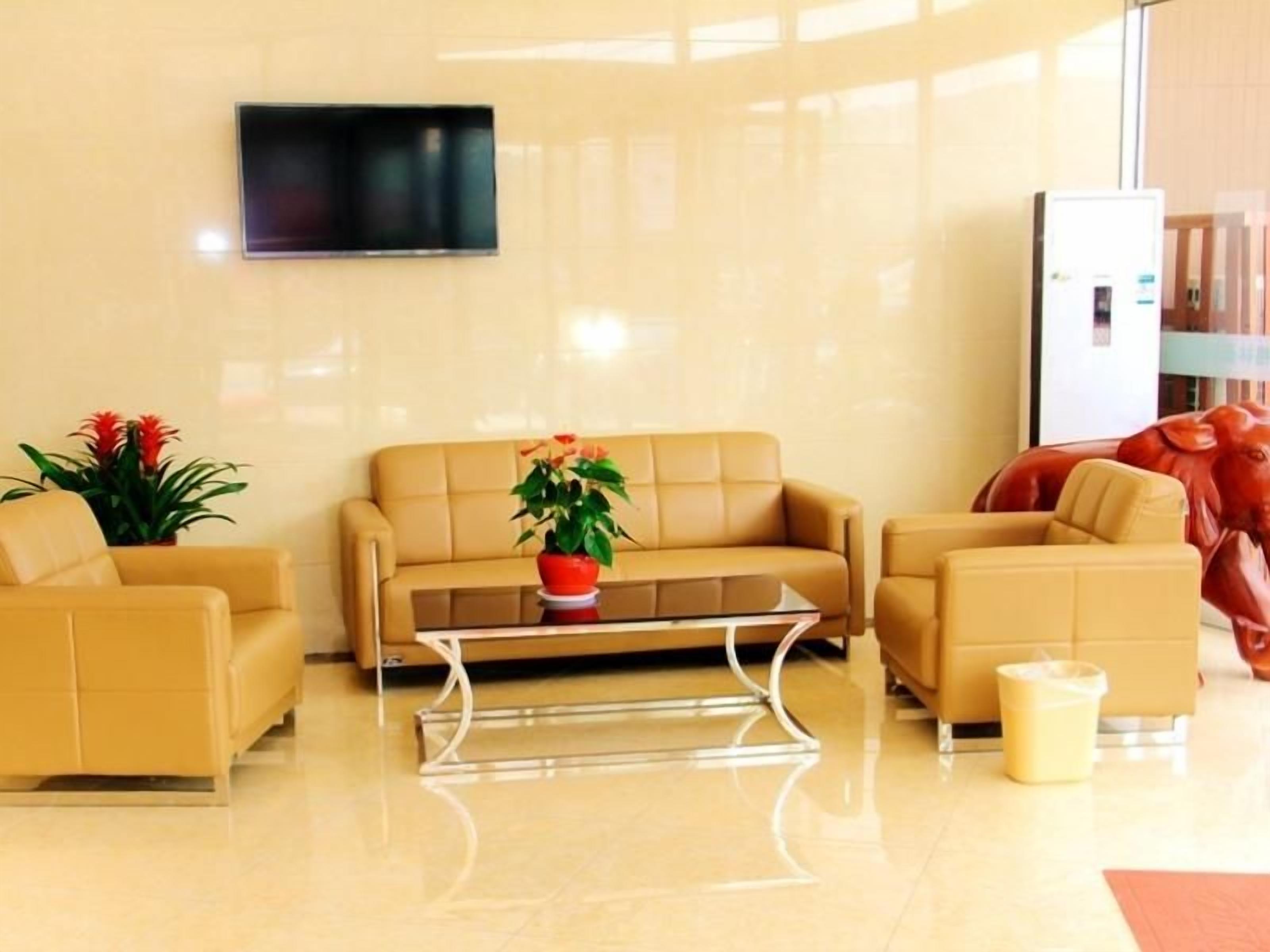 A modern lobby with a beige sofa set, a glass coffee table, and a red sculpture.