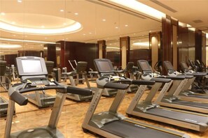 Ein Fitnessraum mit mehreren Laufbändern, jeweils ausgestattet mit einem digitalen Bildschirm.