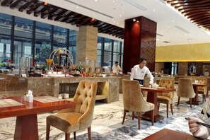 Un vestíbulo moderno de hotel con piso de mármol, un mostrador de recepción central y zonas de estar.