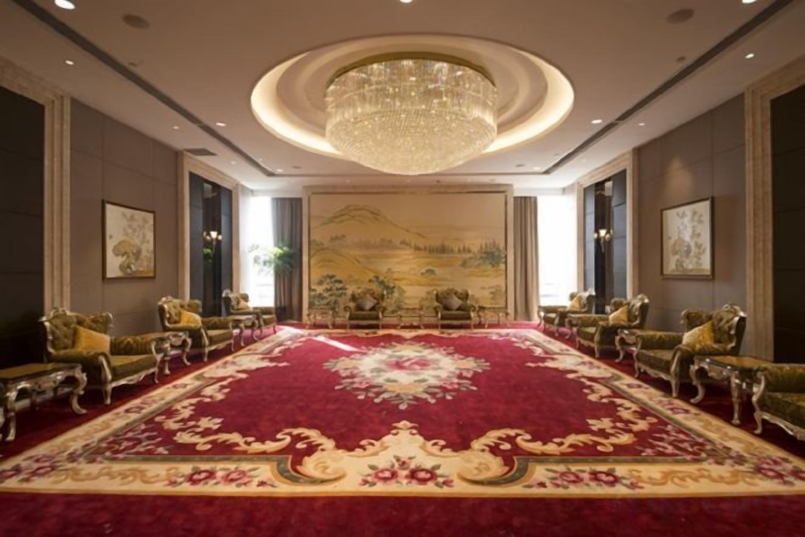 A spacious room with a large red carpet, ornate furniture, and a chandelier.