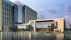 Een modern hotel met een glazen gevel, een zwembad en een verzorgde tuin.