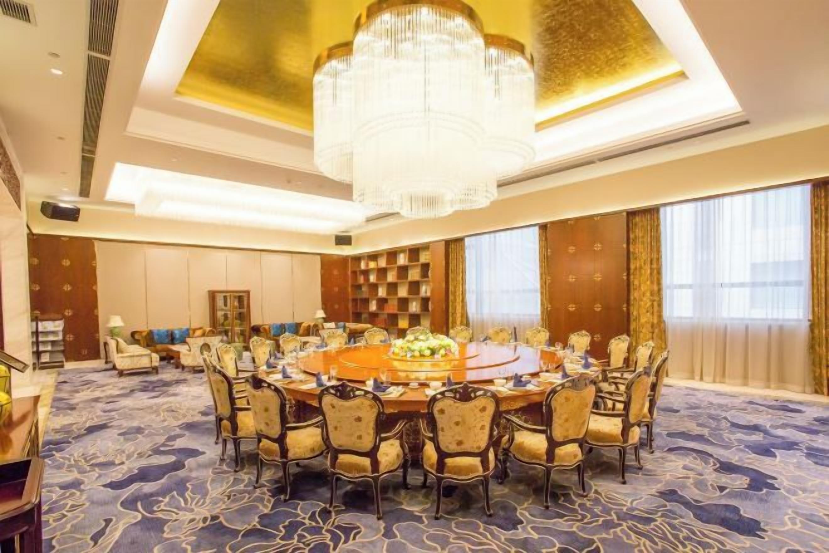 A conference room with a round table, chairs, and a chandelier.