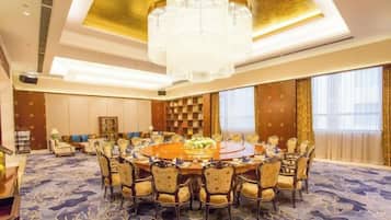 A conference room with a round table, chairs, and a chandelier.