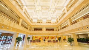 Een ruime lobby met een hoge plafond, verschillende niveaus en een centraal zitgedeelte.