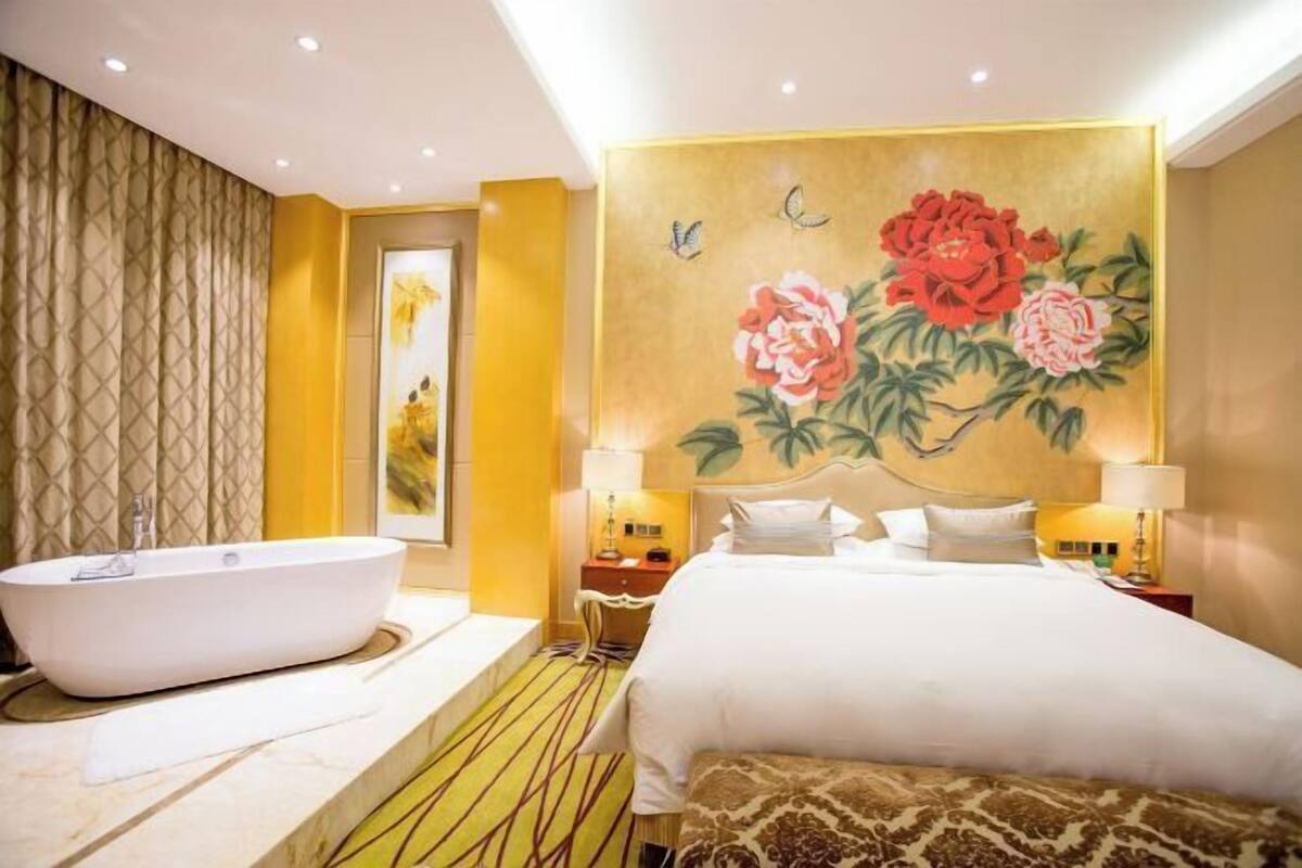 Une chambre d’hôtel avec un grand lit, une baignoire et une peinture murale représentant des fleurs et des papillons.