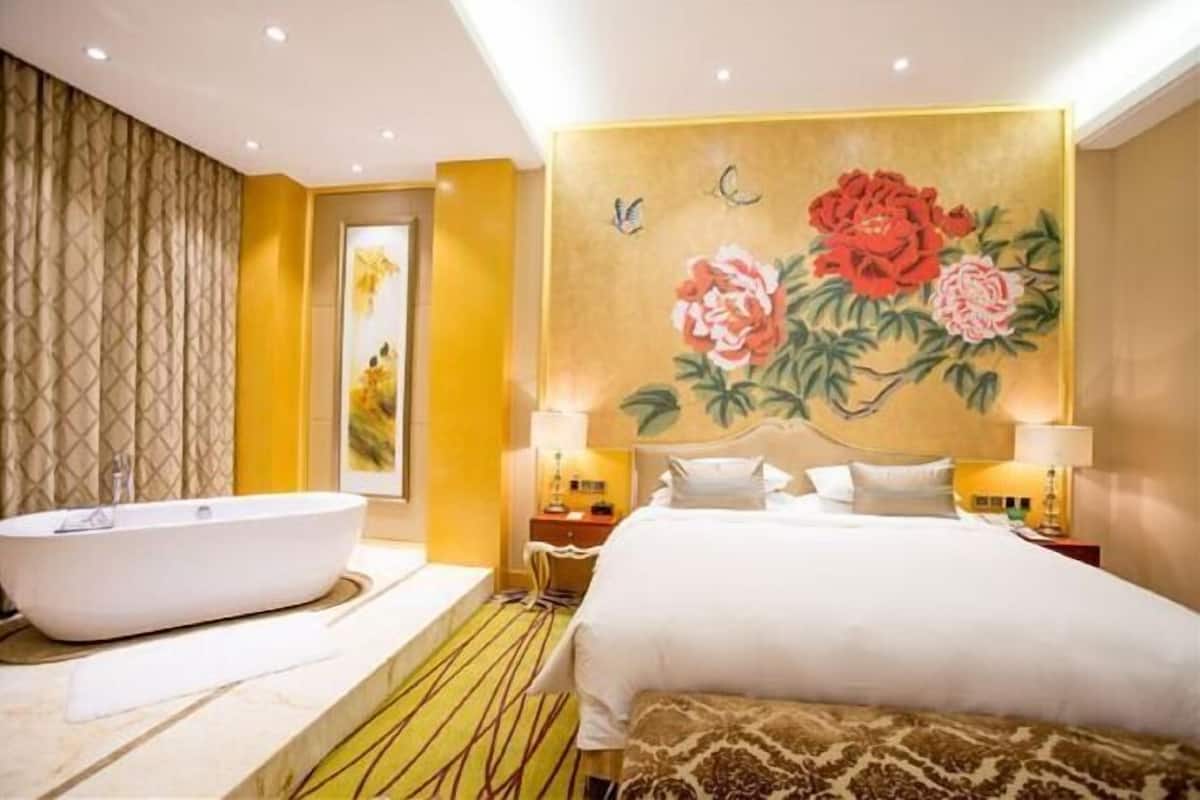 Une chambre d’hôtel avec un grand lit, une baignoire et un mur décoré de motifs floraux.