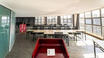 A spacious conference room with multiple tables and chairs, large windows, and a red tray table.