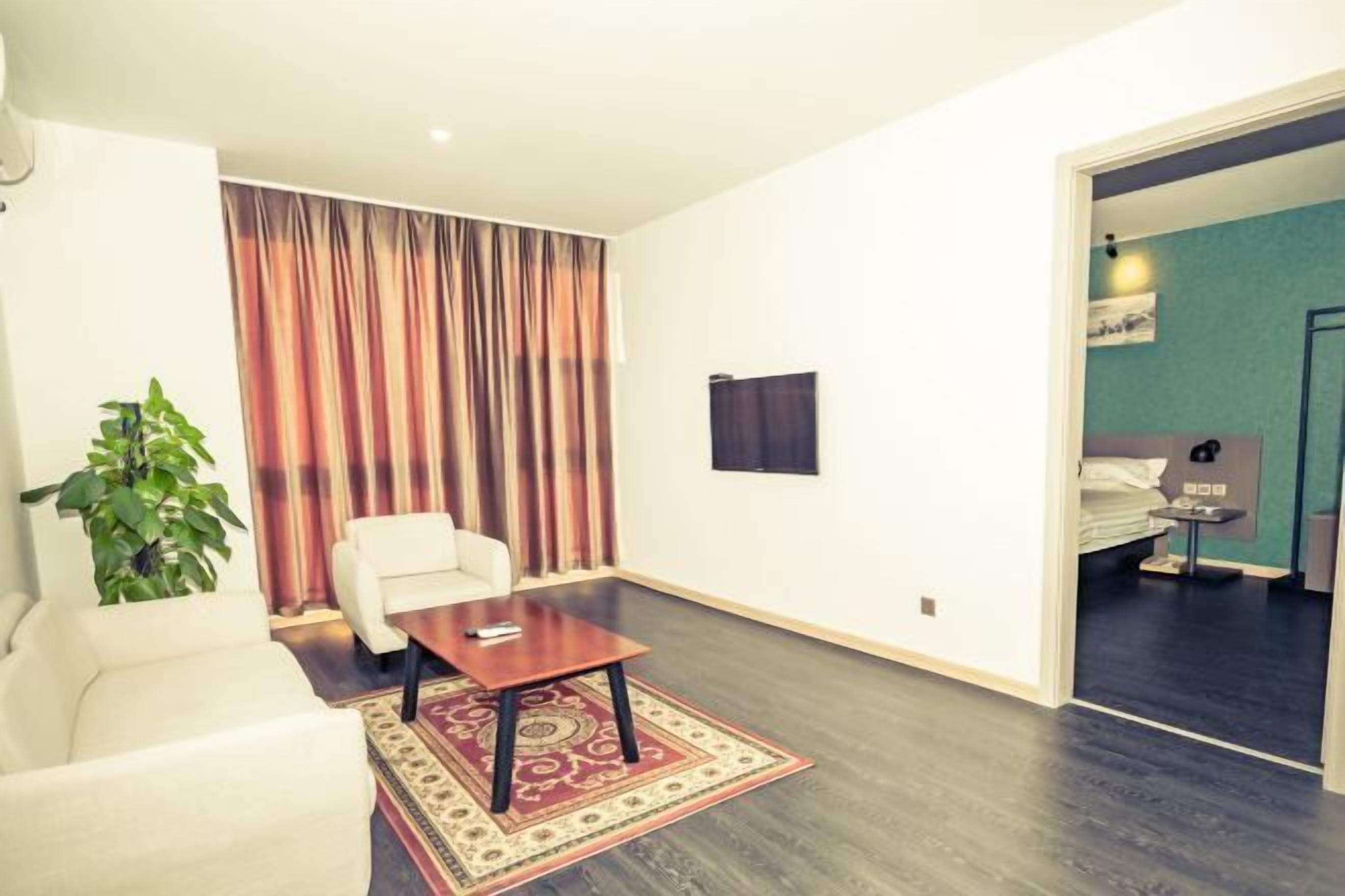 A modern hotel room with a large window, a sofa, a small table, and a bed.