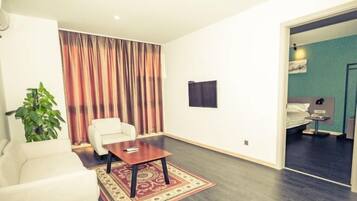 A modern hotel room with a large window, a sofa, a small table, and a bed.