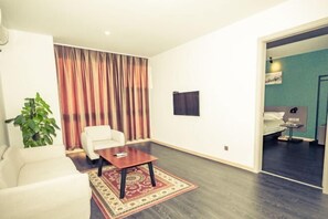 A modern hotel room with a large window, a sofa, a small table, and a bed. - Jinjiang Inn Style (Jiaxing Tanghui Yuehe Scenic Hotel ) (Jiaxing)