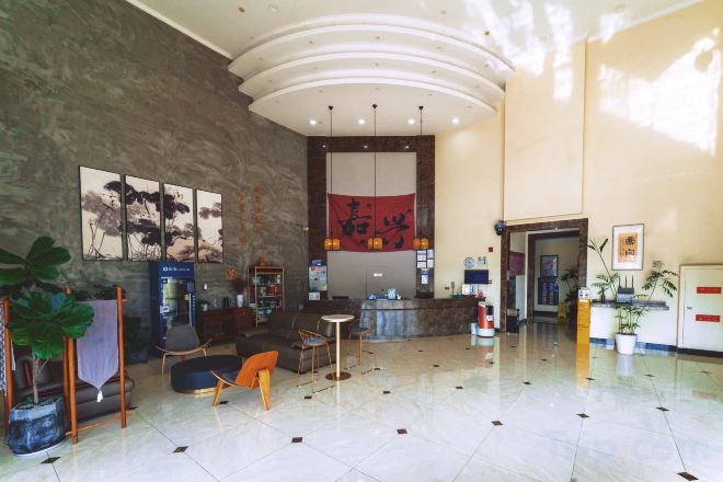 Un vestíbulo amplio con mostrador de recepción, zona de estar y obras de arte en las paredes.