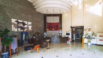 A spacious lobby with a reception desk, seating area, and artwork on the walls.