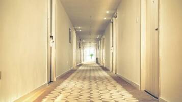 Un largo y estrecho pasillo de hotel con puertas a ambos lados y una alfombra estampada.