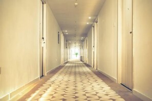 A long, narrow hotel corridor with doors on both sides and a patterned carpet.