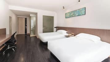 A hotel room with two beds, a desk, and a chair.