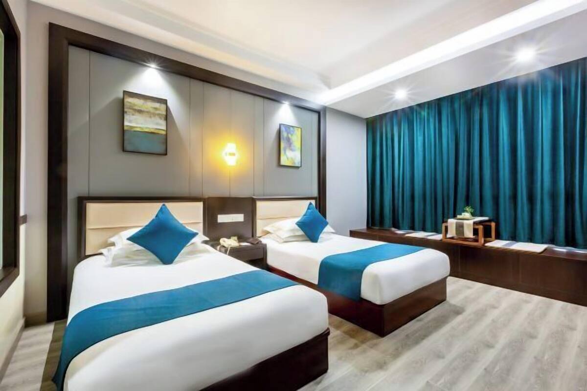 Une chambre d’hôtel avec deux lits, un bureau, une chaise, une table de chevet et une grande fenêtre.