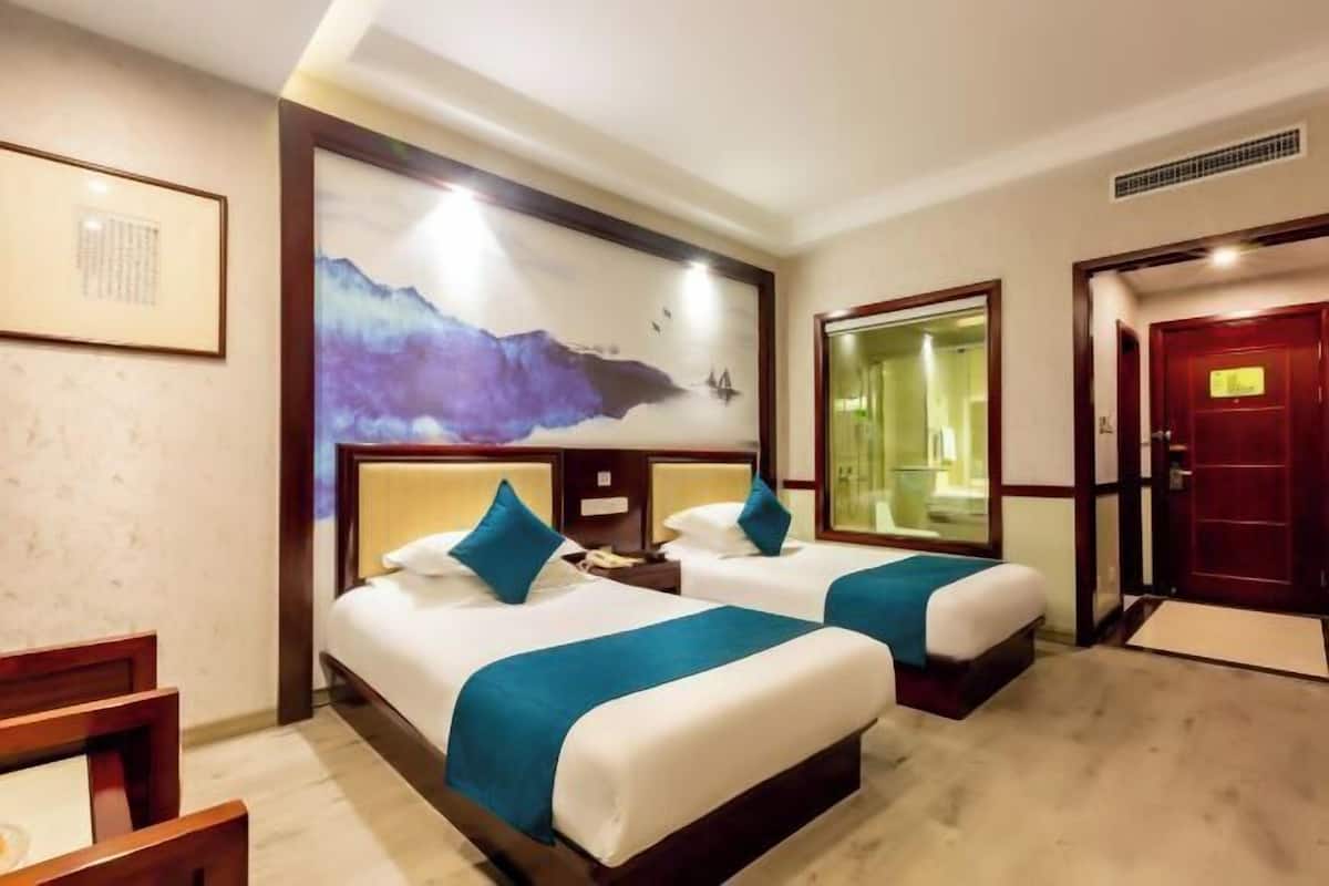 Une chambre d’hôtel avec deux lits, une grande peinture abstraite au mur, une porte en bois et un petit bureau avec une chaise.
