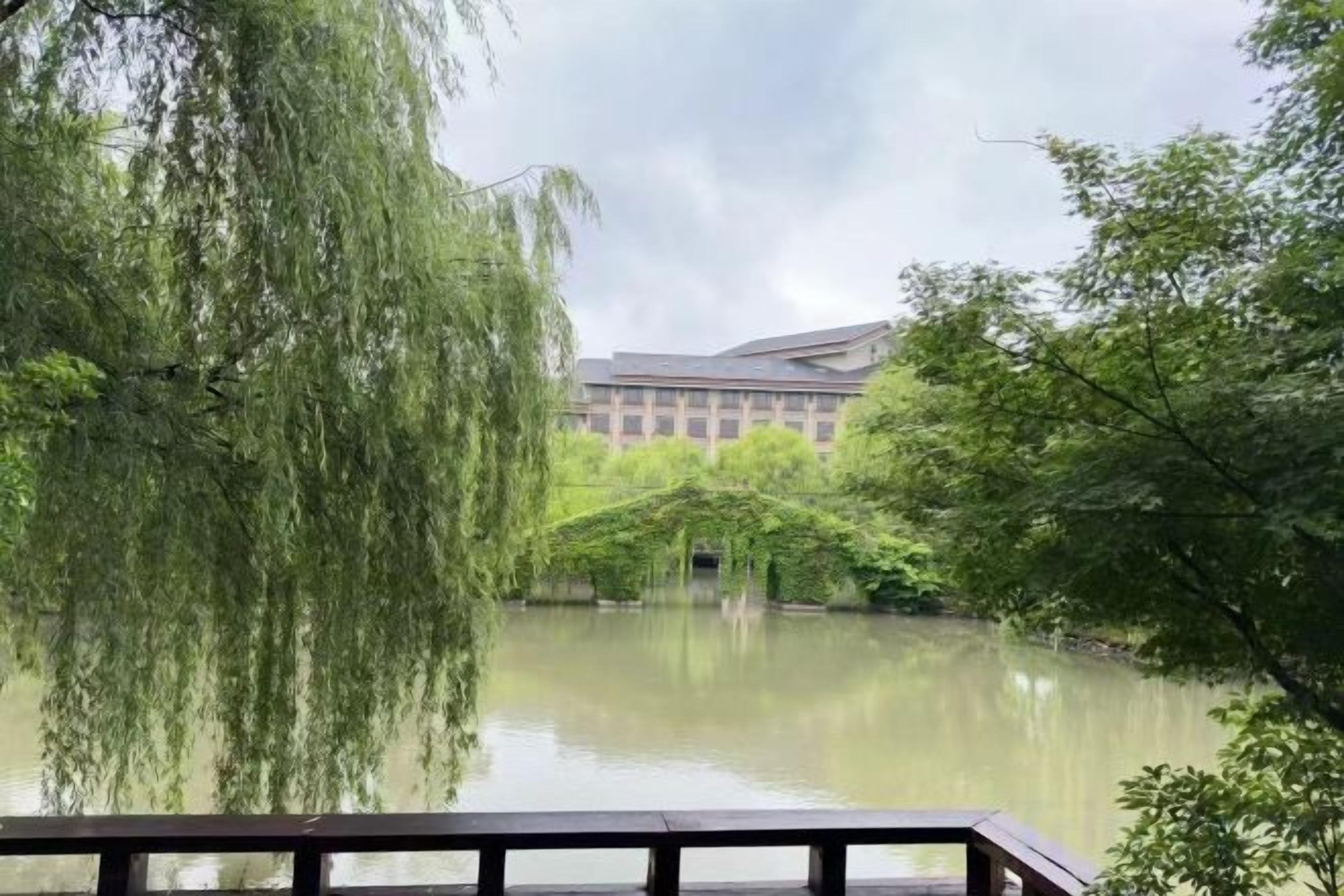 A calm lake with a wooden deck in the foreground and a building in the background.