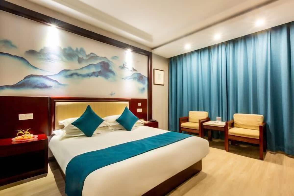 Une chambre d’hôtel avec un grand lit, une table de chevet, un bureau, deux chaises et un tableau au mur.