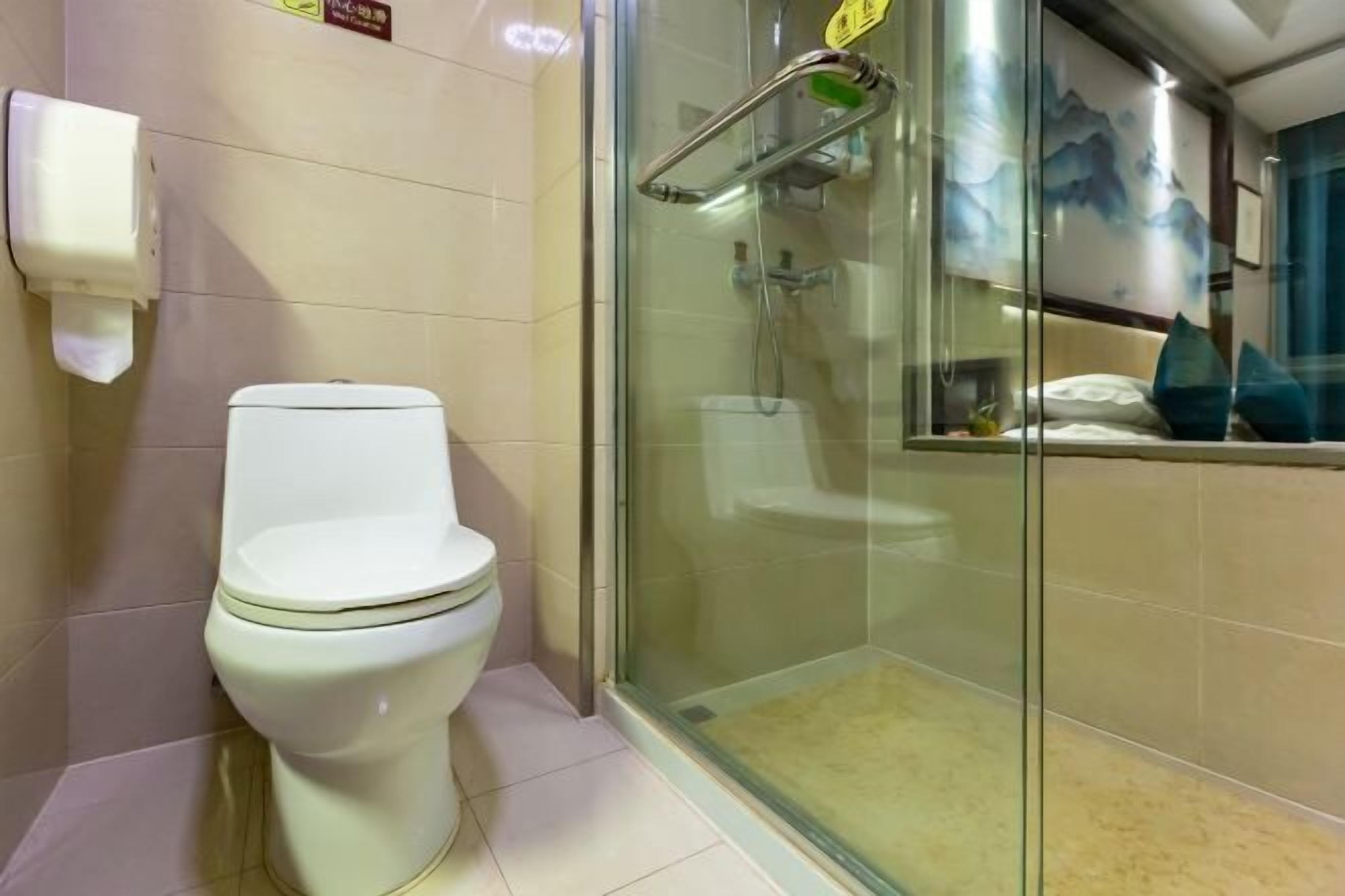 A modern bathroom with a toilet, a glass shower enclosure, and a hand dryer.