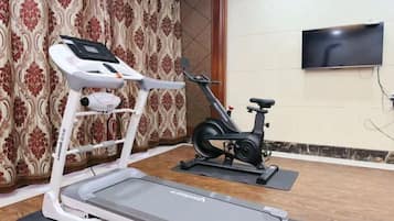Een huisgymnasium met een loopband, elliptische trainer en een hometrainer.