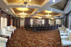 A conference room with rows of chairs, a large screen, and a chandelier. - Guanfeng Holiday Hotel (Tongxiang)