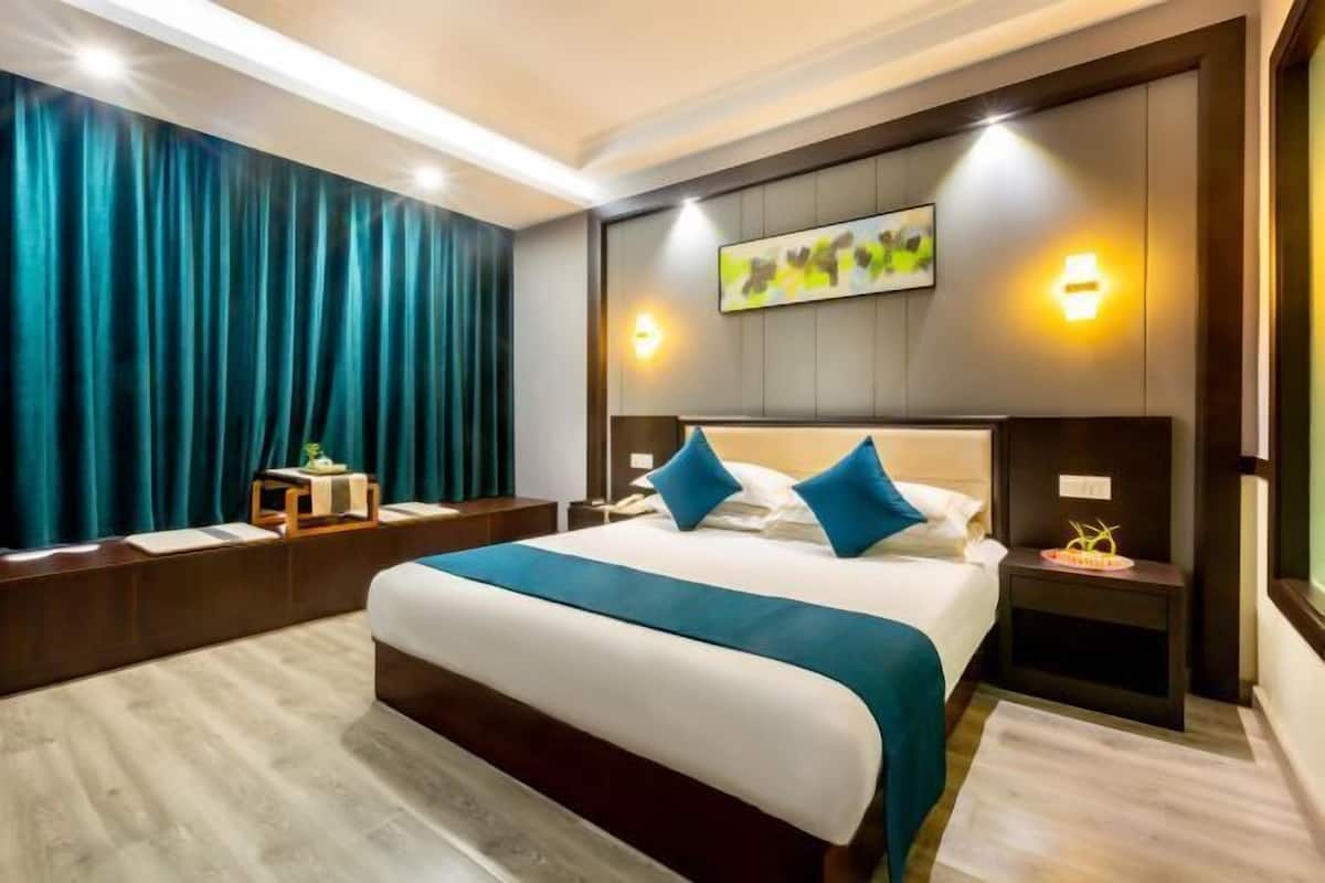 Une chambre d’hôtel moderne avec un grand lit, une tête de lit en bois foncé et une vue sur la ville.
