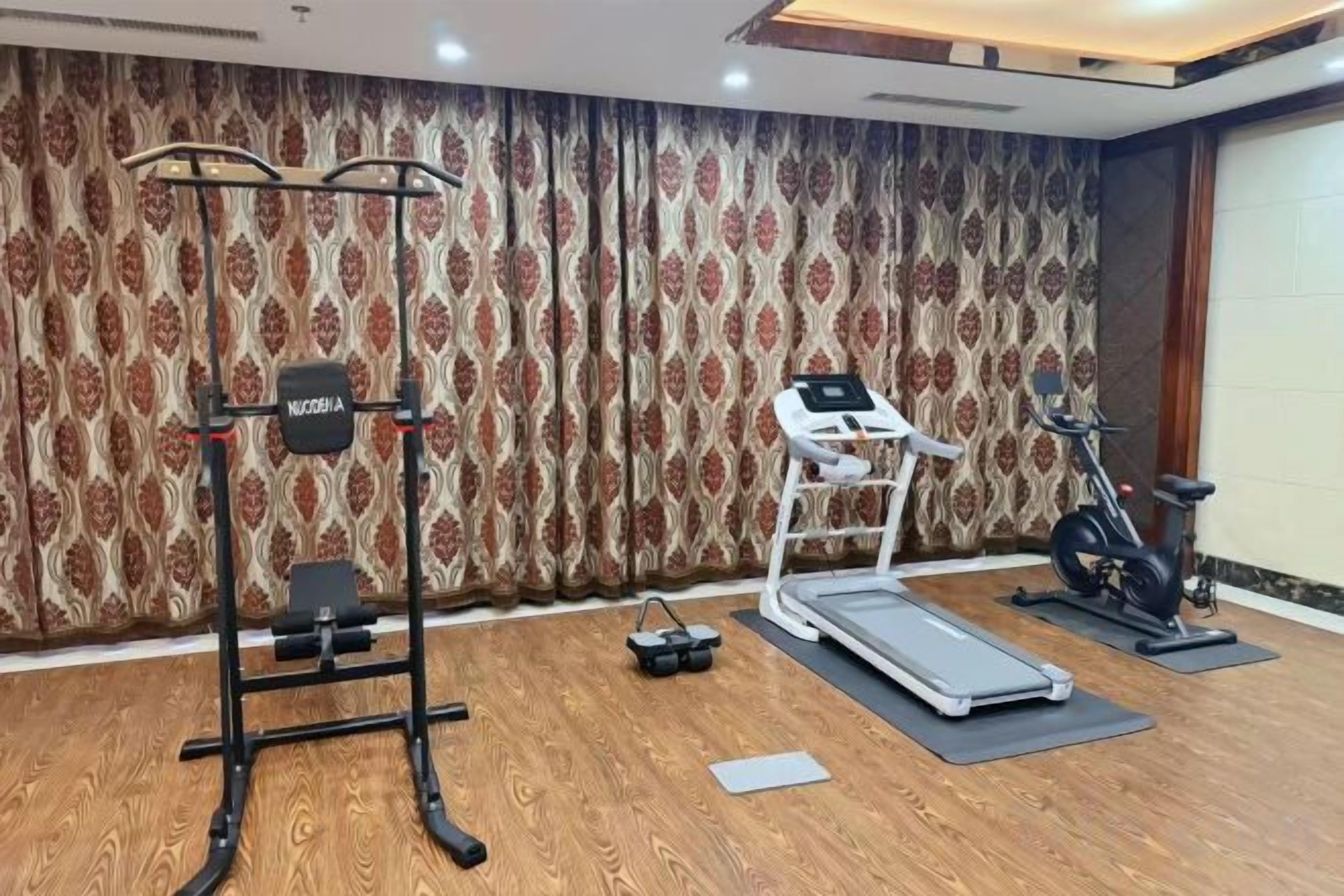 A gym with exercise equipment including a treadmill, stationary bike, and weight machine.