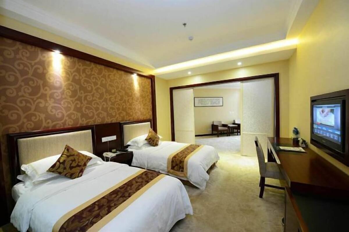 Une chambre d’hôtel avec deux lits, une télévision et un bureau.