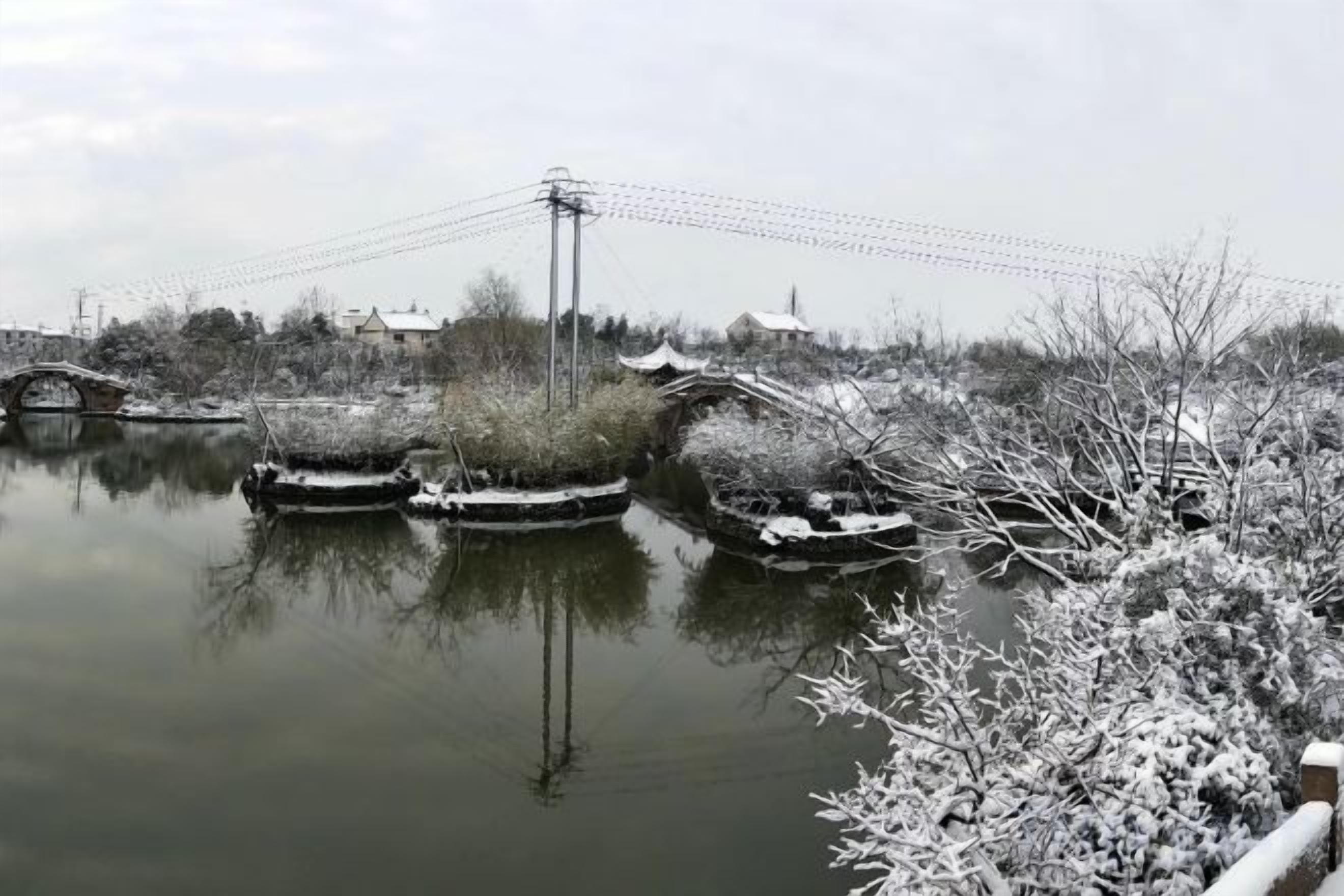 Escena hivernal serena amb un riu gelat, arbres coberts de neu i un pont.