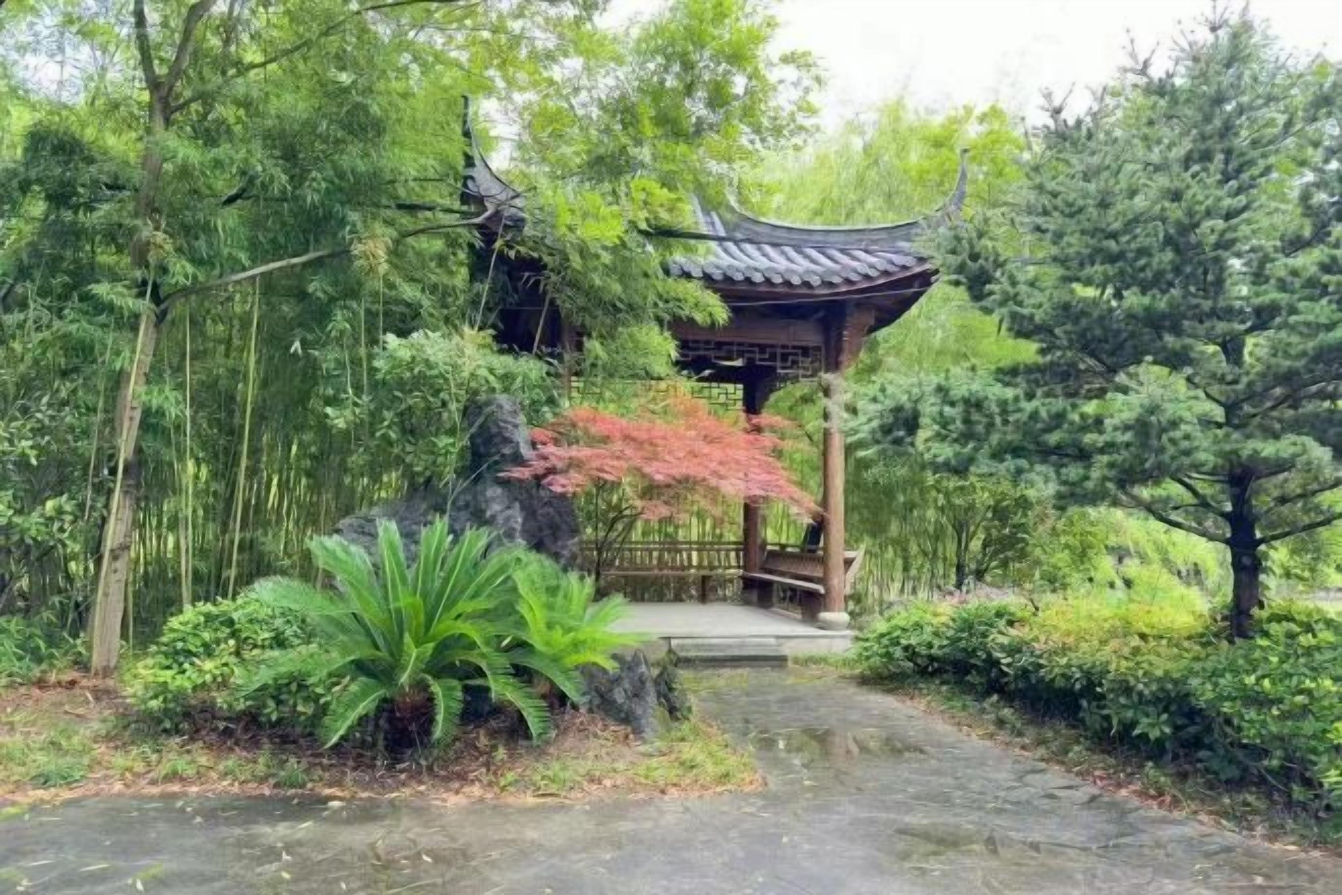 Un pavillon traditionnel, doté d’un toit en tuiles, entouré d’une végétation luxuriante et bordé d’un sentier en pierre.