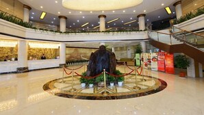 A spacious lobby with a central fountain, multiple levels, and a staircase. - Guanfeng Holiday Hotel (Tongxiang)