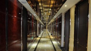 A long, narrow hallway with reflective floors and dark-toned walls, leading to closed doors on both sides. - Guanfeng Holiday Hotel (Tongxiang)