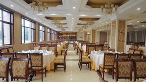 A spacious banquet hall with rows of tables and chairs, large windows, and chandeliers. - Guanfeng Holiday Hotel (Tongxiang)