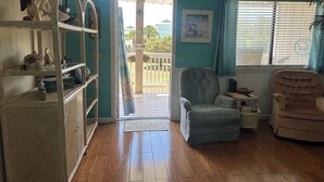 A cozy living room with a wooden floor, a grey armchair, a beige armchair, and a wooden cabinet with decorative items.