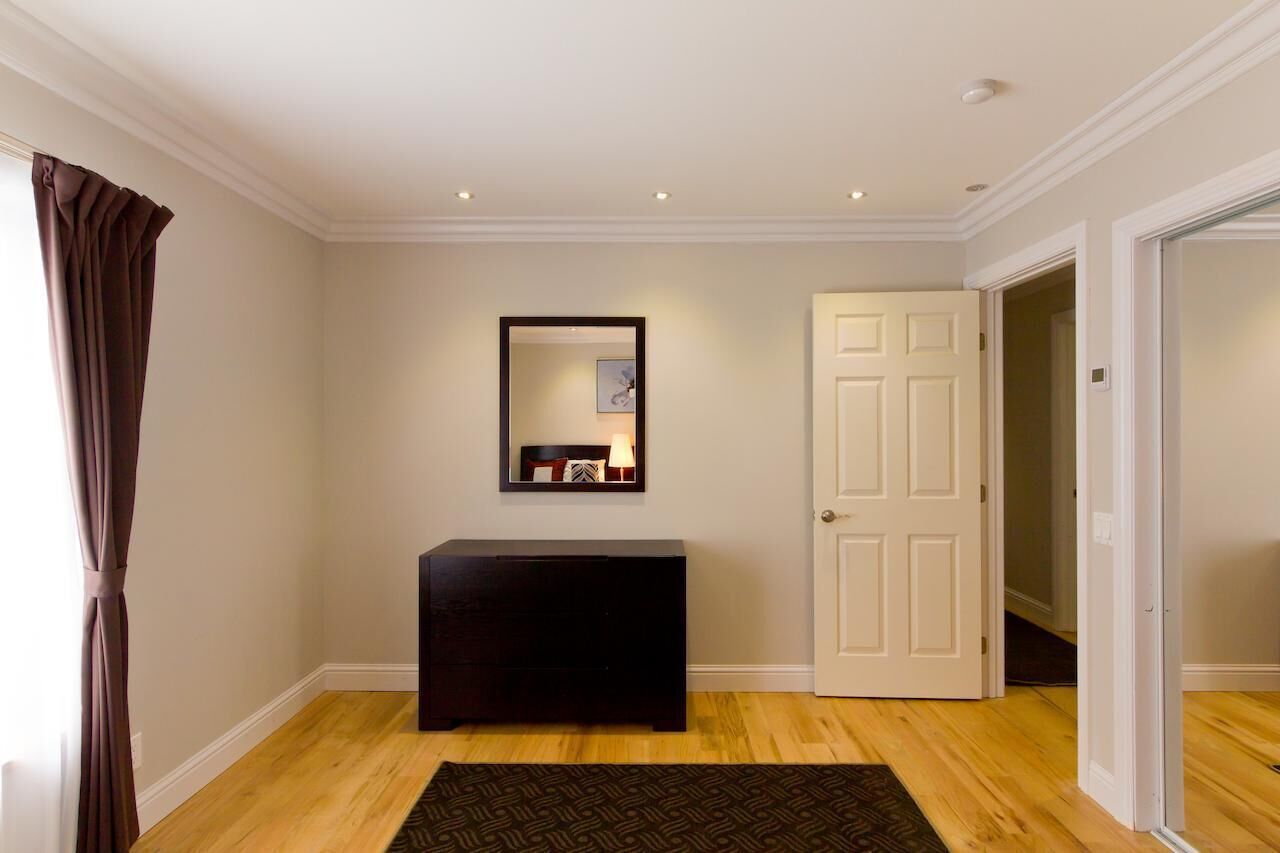 A hallway with a dark console table, a framed picture above it, and a white door on the right.