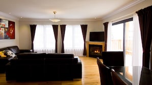 Ein Wohnzimmer mit einer Couch, einem Kamin und einem großen Fenster mit Vorhängen.