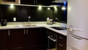 Eine moderne Küche mit dunklen Schränken, einem Edelstahl-Kühlschrank, einer Mikrowelle und einem eingebauten Ofen.