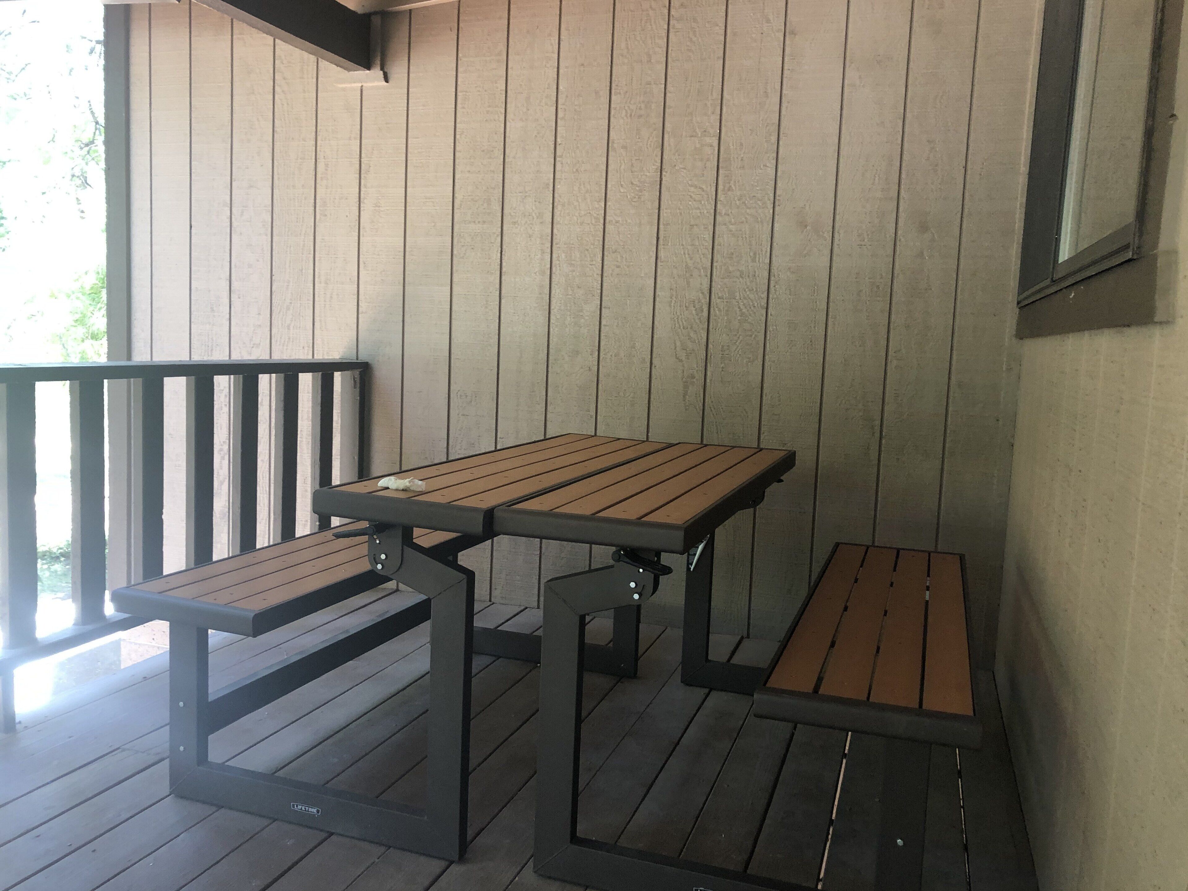 Un espace extérieur abrité, aménagé avec une table en bois et des bancs.