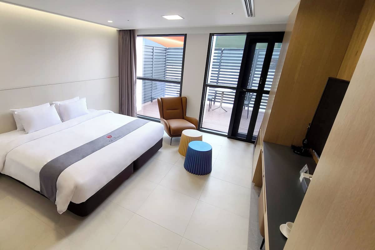 Een hotelkamer met een bed, een stoel, een kleine tafel en een televisie.