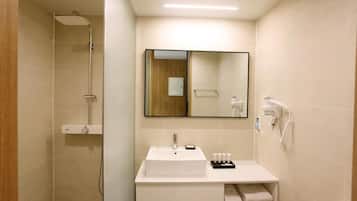 A modern bathroom with a white sink, a mirror, a shower, and a towel rack.