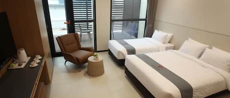 Habitación de hotel con dos camas, un escritorio, una silla y una mesita con una planta.