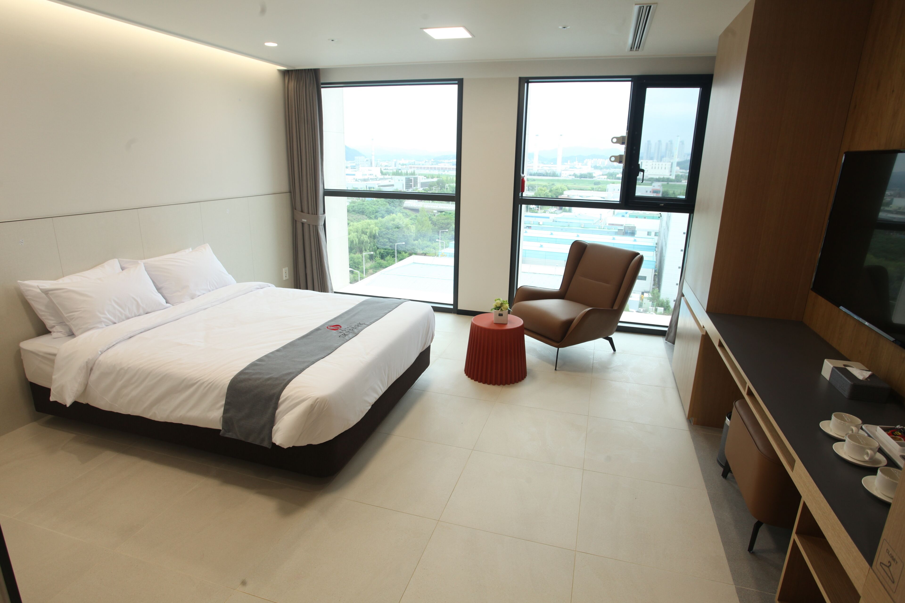 A hotel room with a bed, a desk, a chair, and a TV.