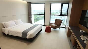 A hotel room with a bed, a desk, a chair, and a TV.