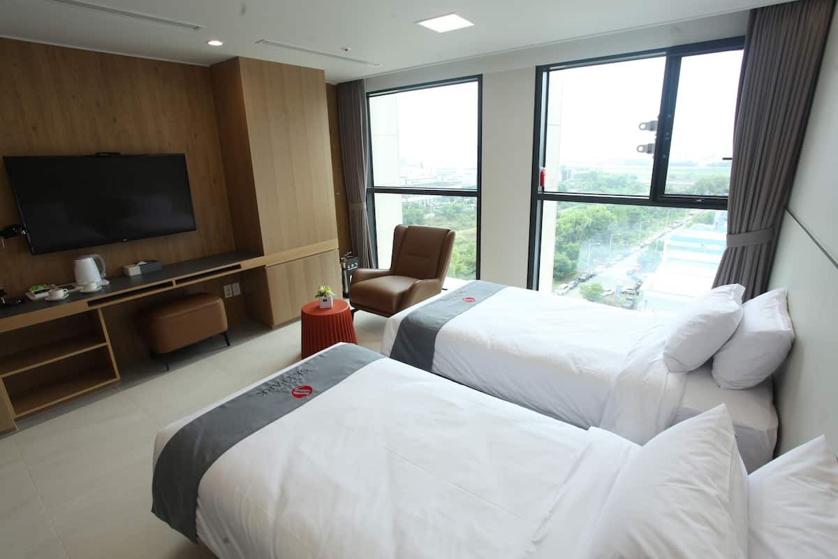 Een hotelkamer met twee bedden, een televisie, een bureau en een stoel.