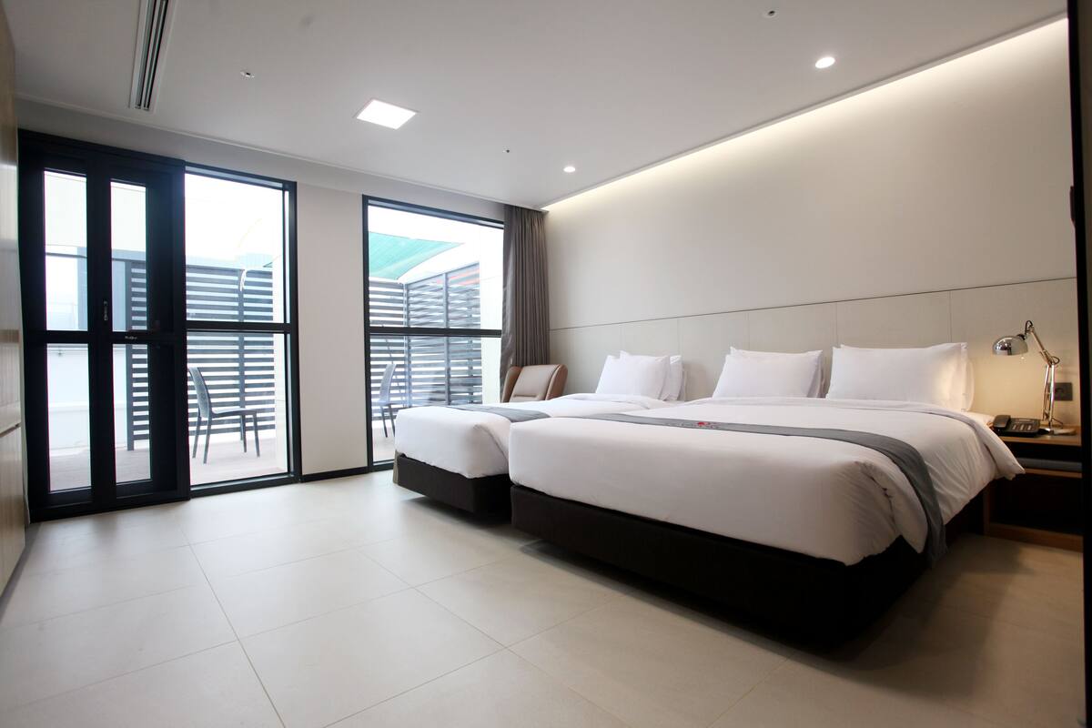 Een moderne hotelkamer met twee bedden, een groot raam en uitzicht op buiten.