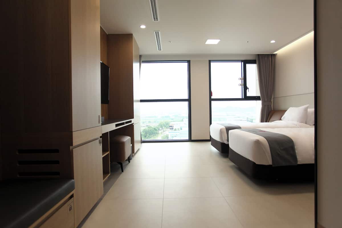 Een hotelkamer met een bed, een televisie, een bureau en grote ramen.