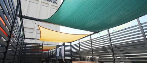 An outdoor seating area with tables and chairs, a SkyPark hotel sign, and a green canopy.