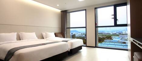 A modern hotel room with a large bed, a view of the city, and a window with blinds.