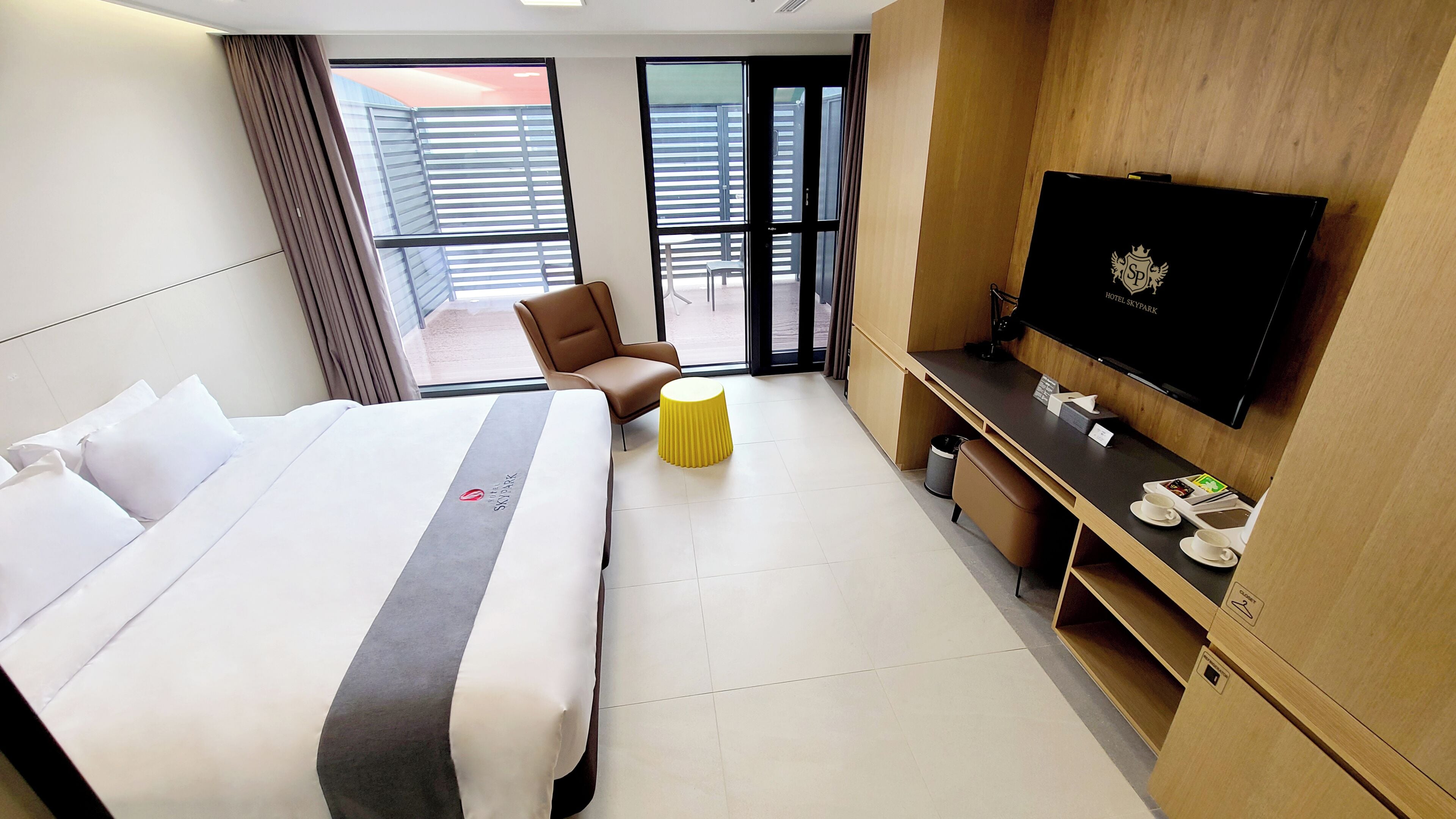 Une chambre d’hôtel avec un lit, une télévision, un bureau, une chaise et une petite table.